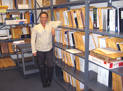 Laurie Roach with shelves of printed dissertations