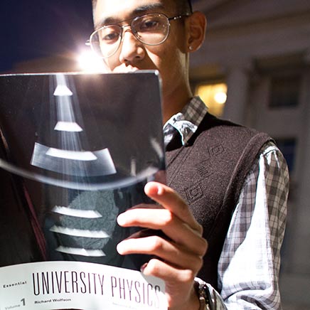 Male with glasses reading a physics textbook
