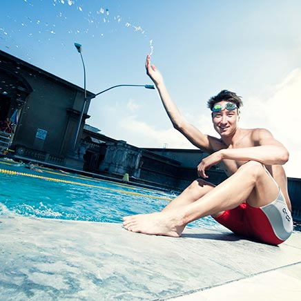 male student sitting next to swimming pool