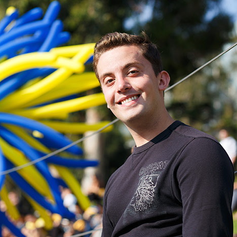Male student wearing black shirt with balloons in background