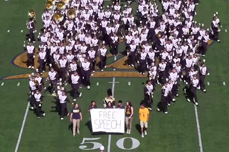 Cal Band members on football field holding a Free Speech banner