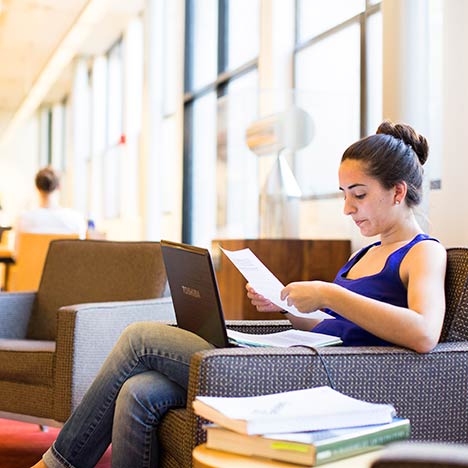 Student sitting in a chair reading a paper