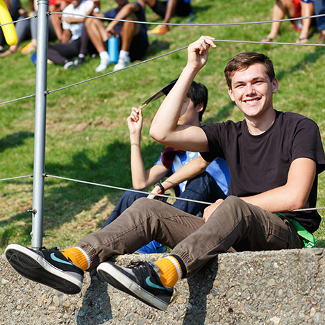 Male student with gold sock sitting on grass