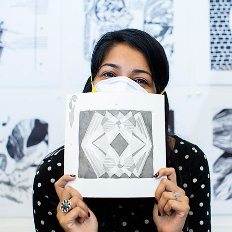 Females wearing a mask and holding up an artwork in front of her face