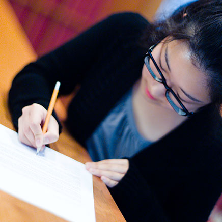 Female wearing glasses and writing on paper