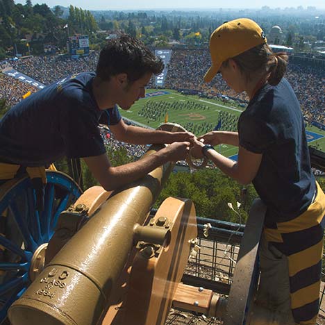 Two people loading a cannon above football field