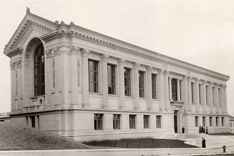 Large three quarter view of building with columns and arched window on side.