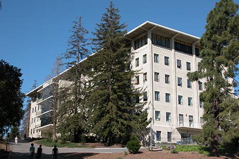 Six story building with trees and people in front