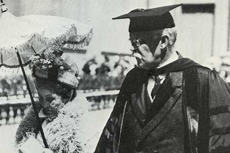 Woman with hat holding parasol and walking beside man wearing scholarly robe and mortarboard