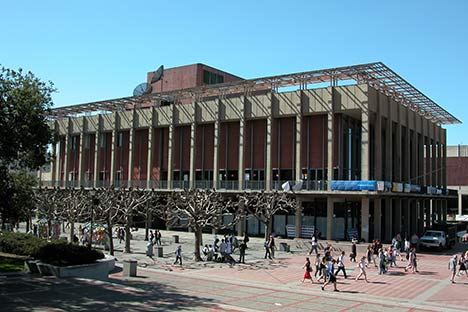 Large two story building with people walking in plaza in front