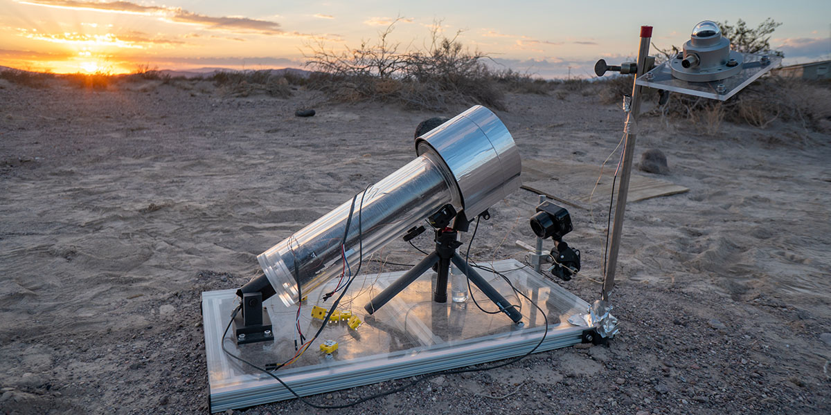 The atmospheric water harvester sits in the sand in Death Valley during a sunset.