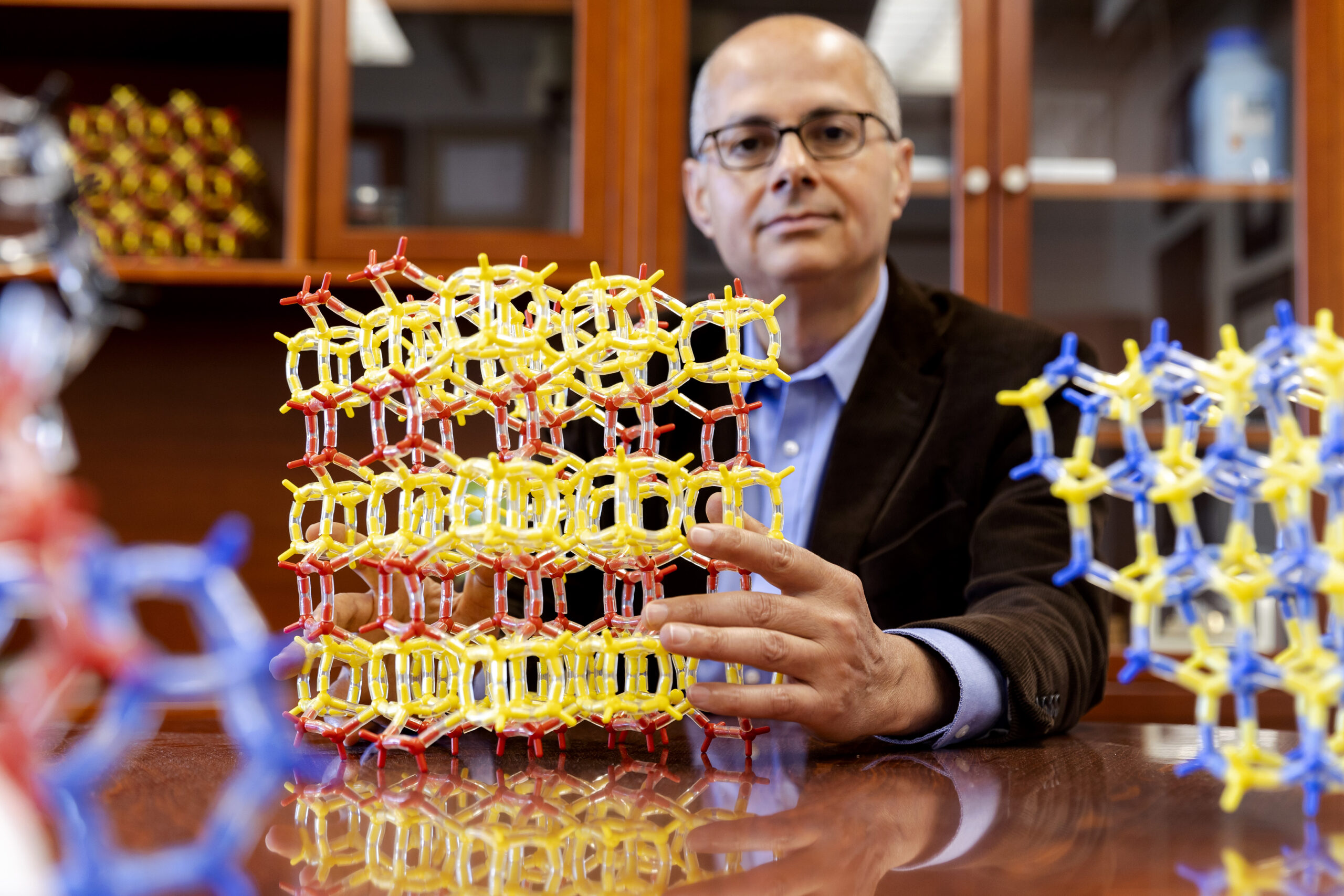 UC Berkeley professor Omar Yaghi sits at a desk in front of a chemical model.